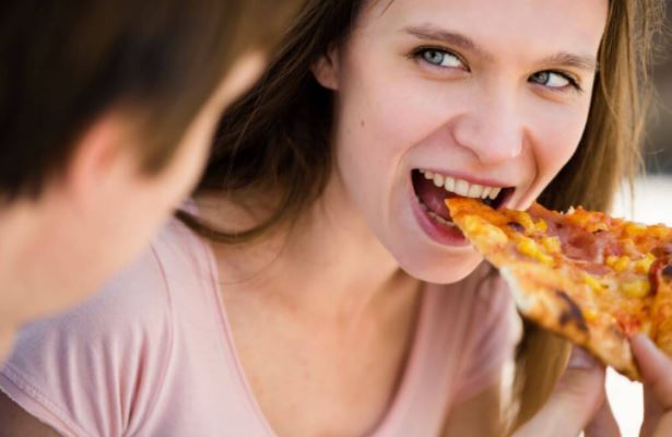 Chica comiendo pizza.