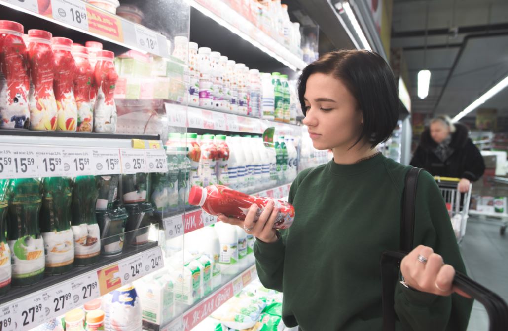 Chica mirando la etiqueta de un producto en el supermercado.