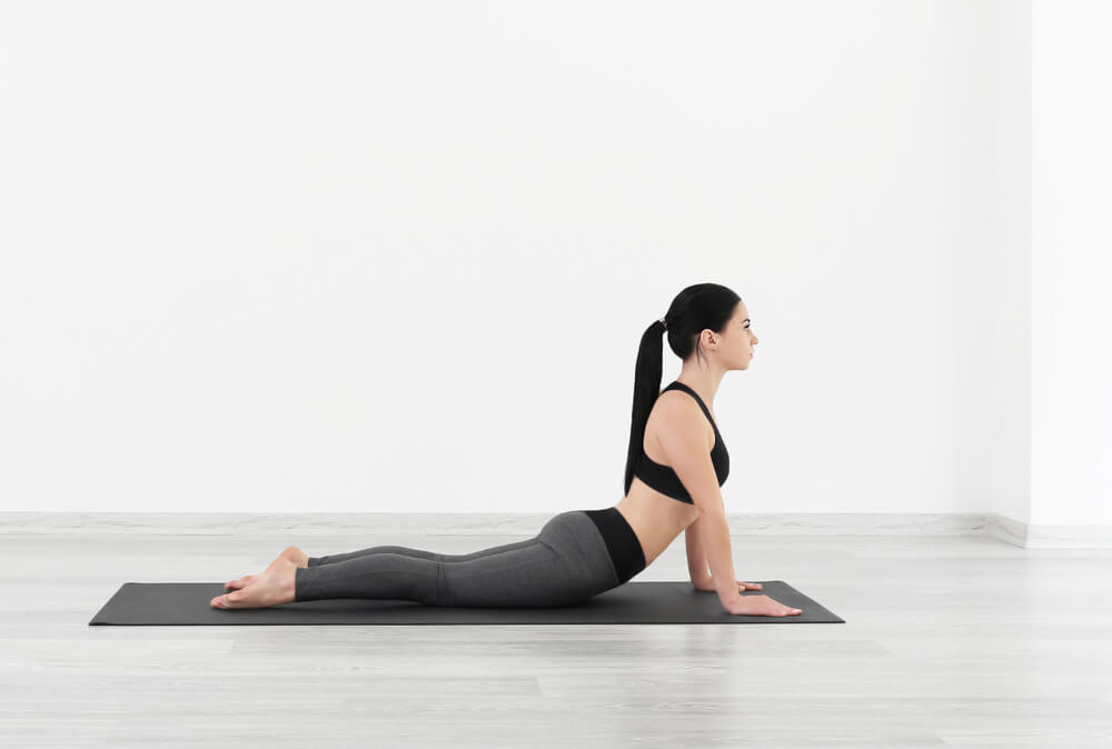 mujer realizando postura cobra yoga