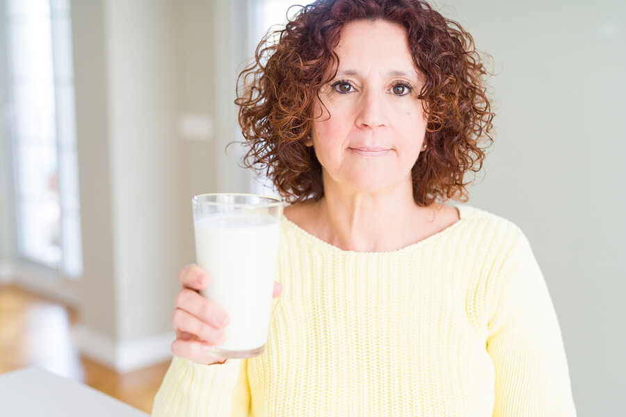 Mujer de edad avanzada toma leche para el fortalecimiento de los huesos.