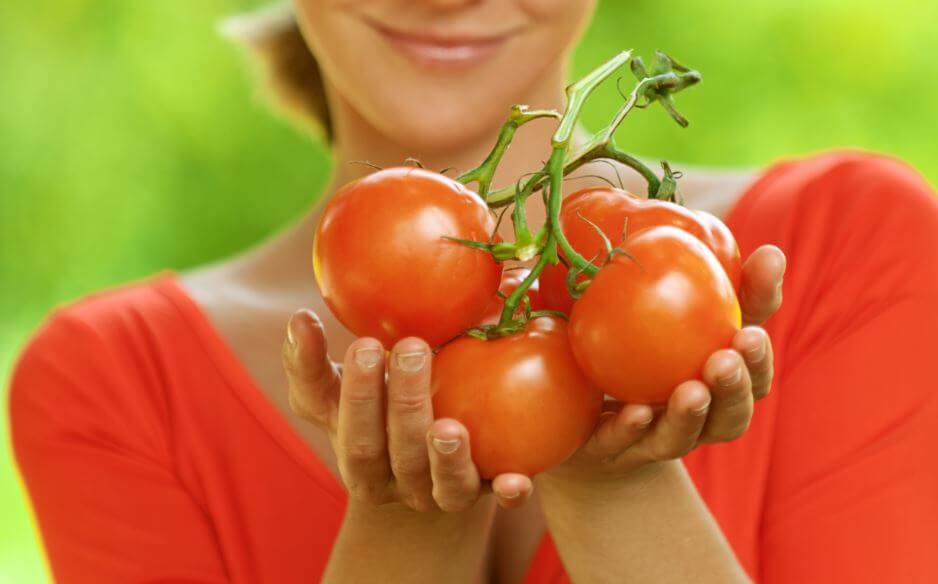 Mujer sostiene tomates ecológicos en sus manos.