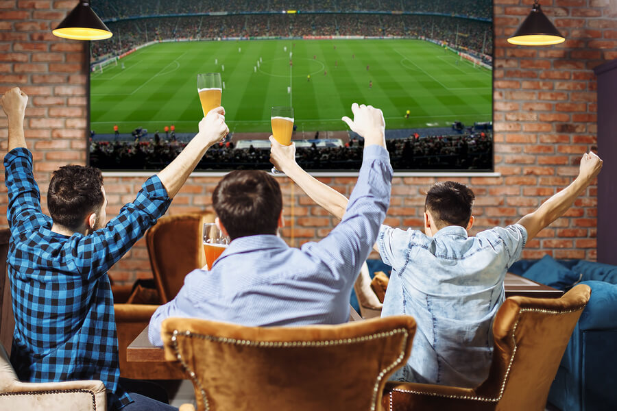 Hombres mirando un partido de fútbol en la televisión.