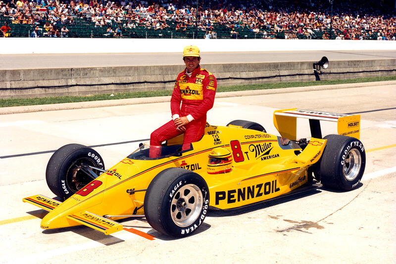 Rick Mears sobre su auto amarillo.