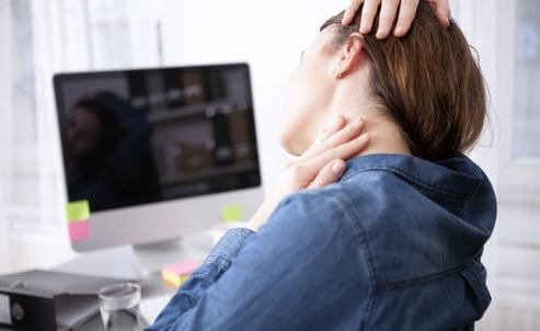 Mujer sufre dolor de cuello durante el teletrabajo.