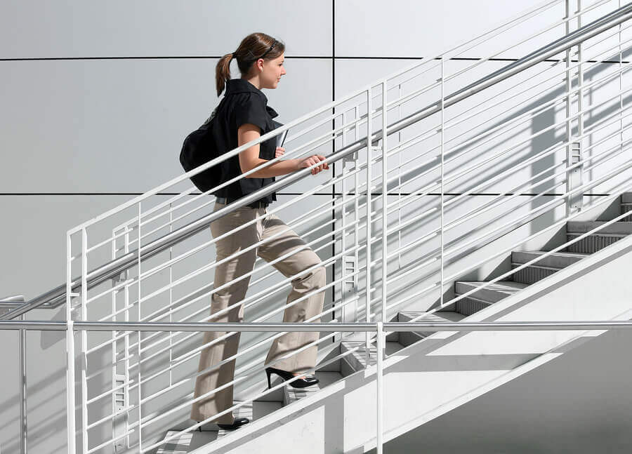 Mujer sube escaleras en el trabajo para mejorar la circulación de las piernas.