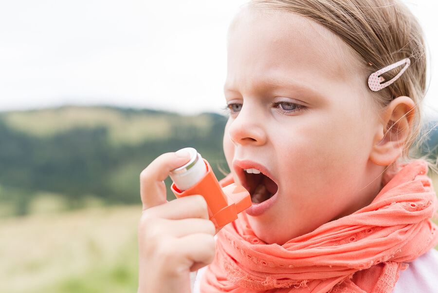 Niña asmática usando su inhalador para combatir los síntomas.