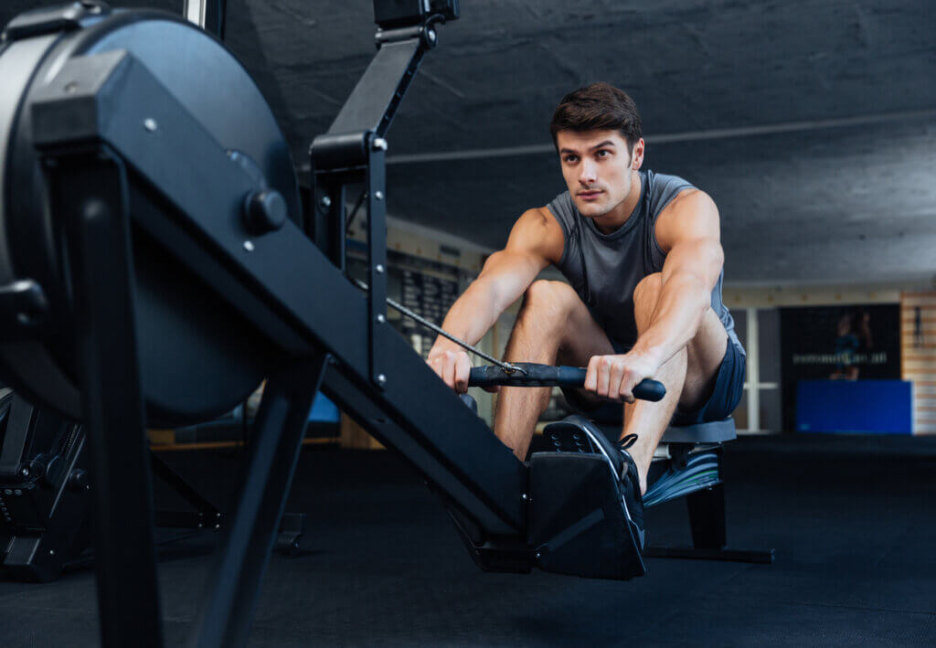 Young man performing anaerobic exercise with a rowing machine.
