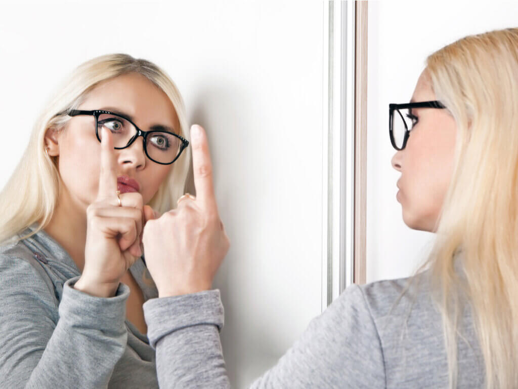Mujer haciendo una autocrítica frente al espejo.