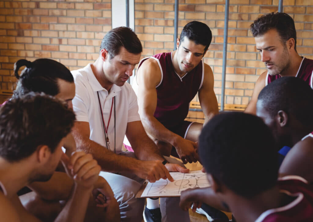 Entrenador de un equipo de baloncesto hablando con sus jugadores.
