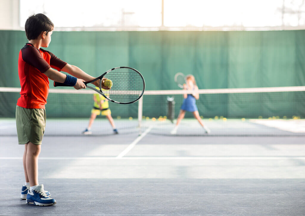 Niño concentrado durante un partido de tenis con público.