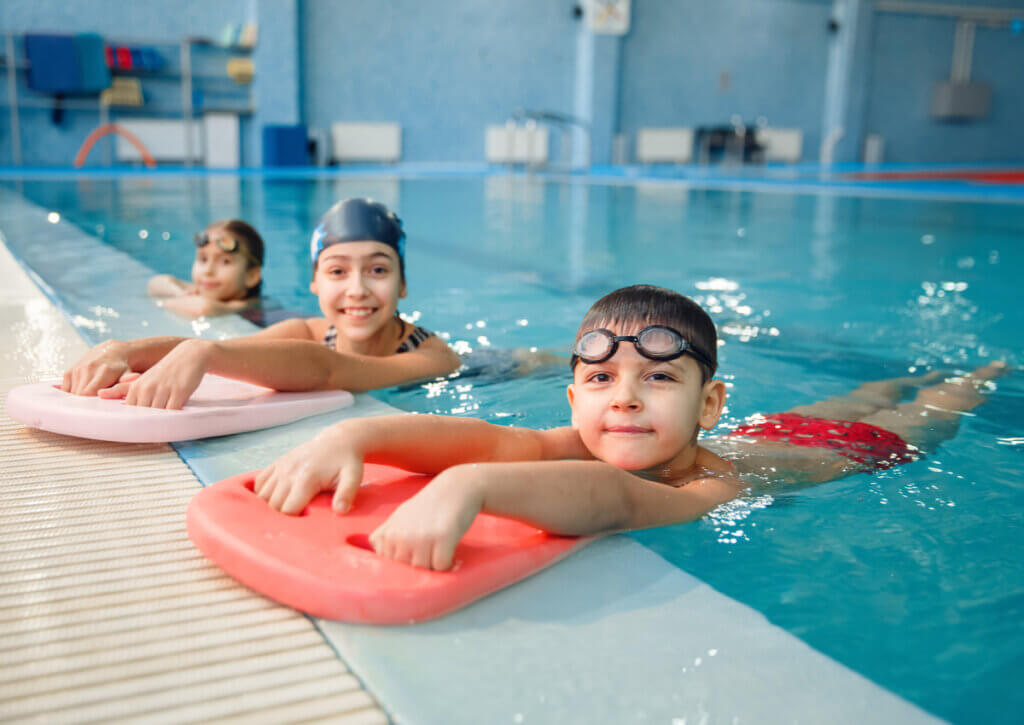 Grupo de infantes realizando ejercicios acuáticos para niños en una piscina.
