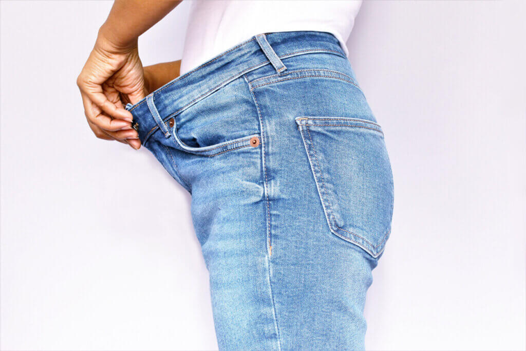 Mujer mostrando su jean holgado tras bajar de peso