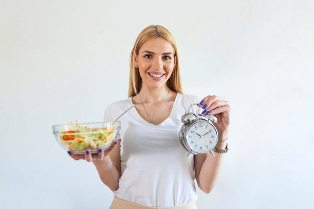 Mujer sosteniendo un plato de ensalada y un reloj