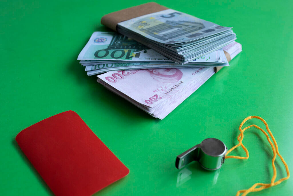 النقود والبطاقة الحمراء والصفارة تمثل التلاعب بنتائج المباريات