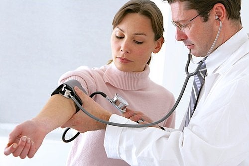 Mujer tomándose la presión con un médico