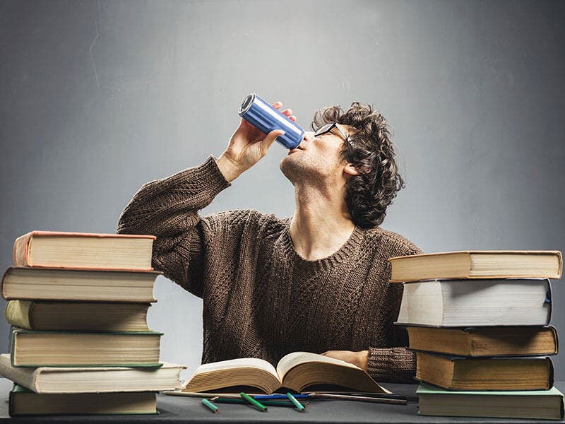 Estudiante bebiendo bebida energética mientras estudia