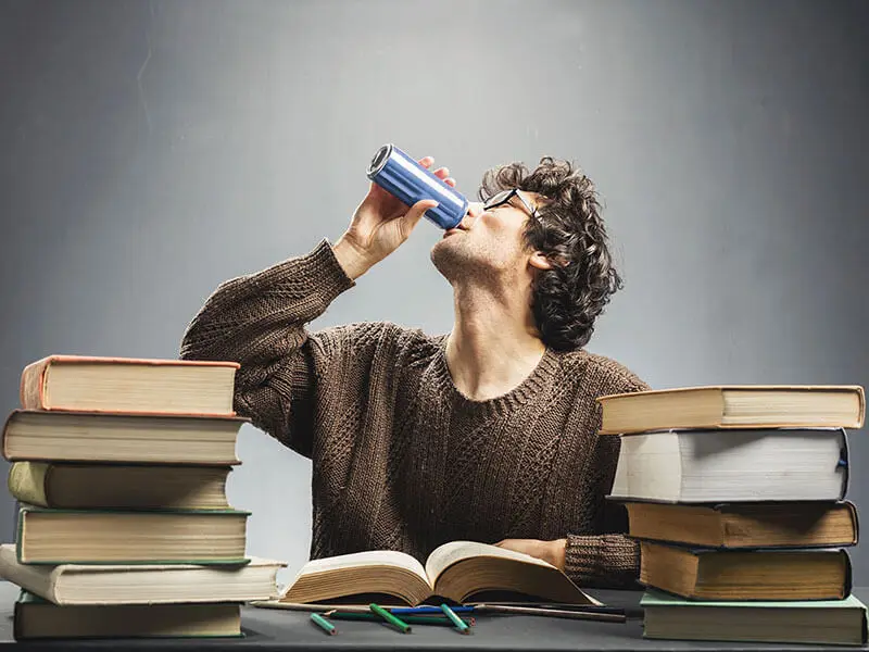 Estudiante bebiendo bebida energética mientras estudia