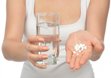 Woman with pills and a glass of water in her hands