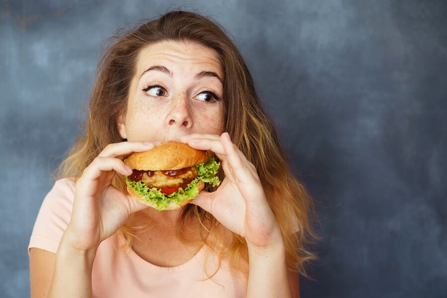 En jente som spiser en hamburger.