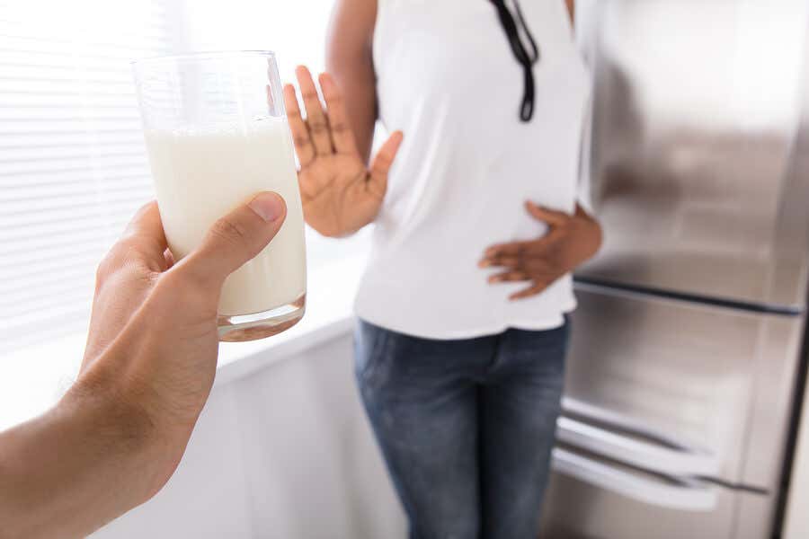 Mujer rechazando vaso de leche por intolerancia.