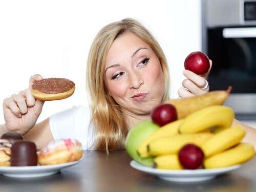 Mujer escogiendo entre comida sana o comida chatarra