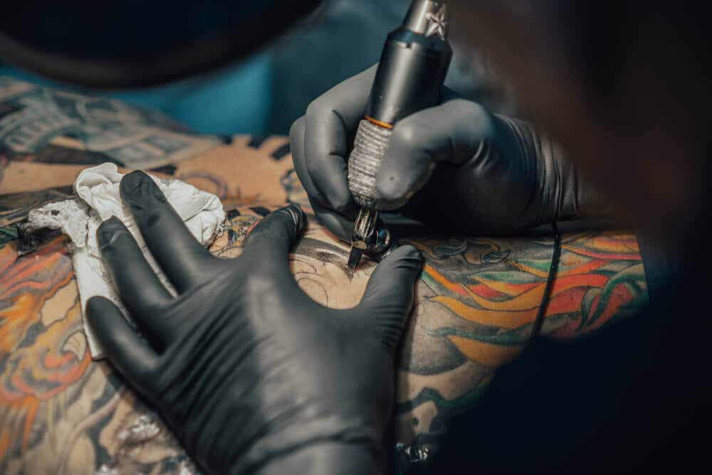 Tatuador haciendo un tatuaje a color.