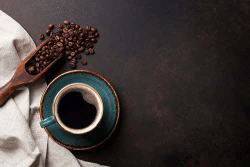 Kaffebønner og en kop kaffe på et bord