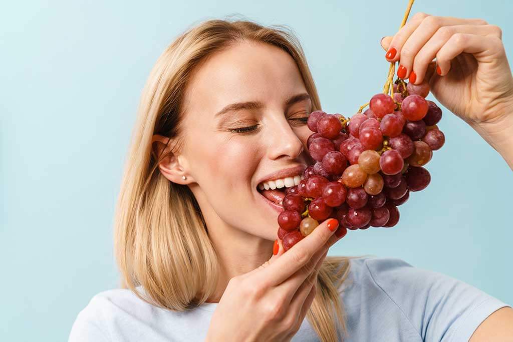 Vrouw eet een tros druiven