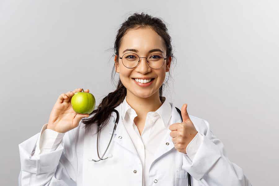 Doctora sosteniendo una manzana verde.