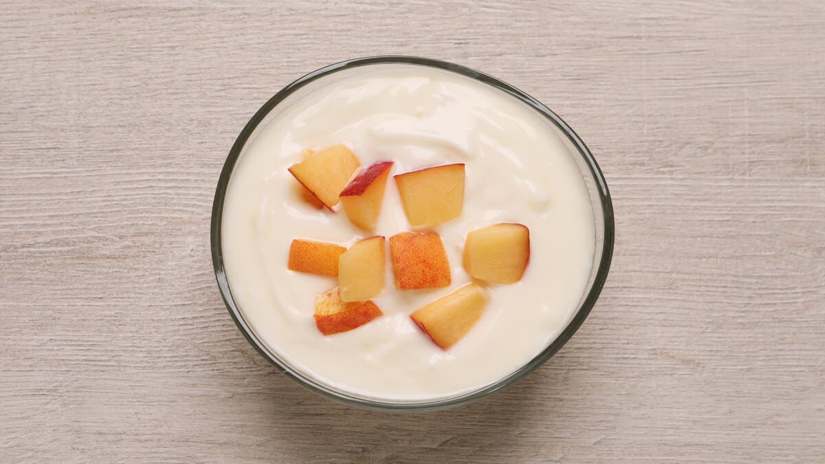 Bol de yogur con trozos de melocotón.