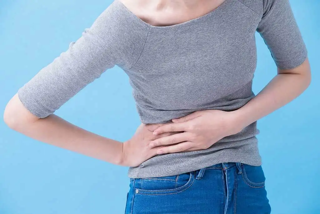 Neue Nebenwirkung von Omeprazol - Frau greift sich an den Bauch