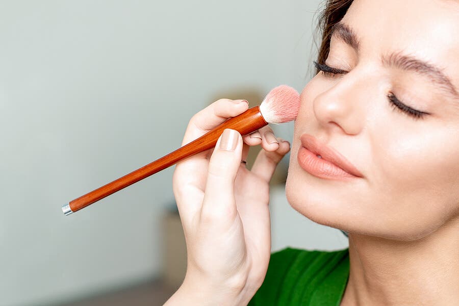 Mujer aplicándose maquillaje para piel seca.