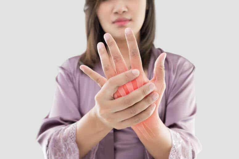 Angeschwollene Finger - Frau hält sich ihre Hand
