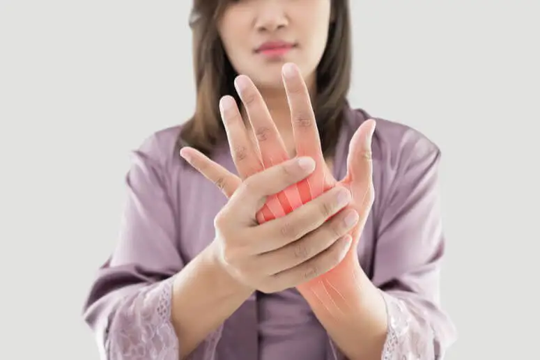 Angeschwollene Finger - Frau hält sich ihre Hand