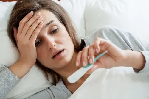 Mujer con fiebre en la cama