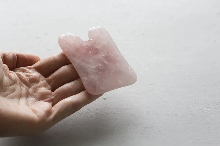 Mano sosteniendo cuarzo rosa.