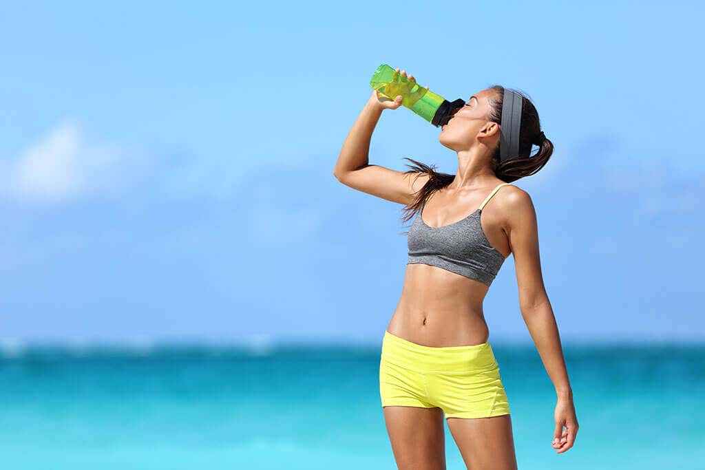 Vrouw drinkt water aan het strand