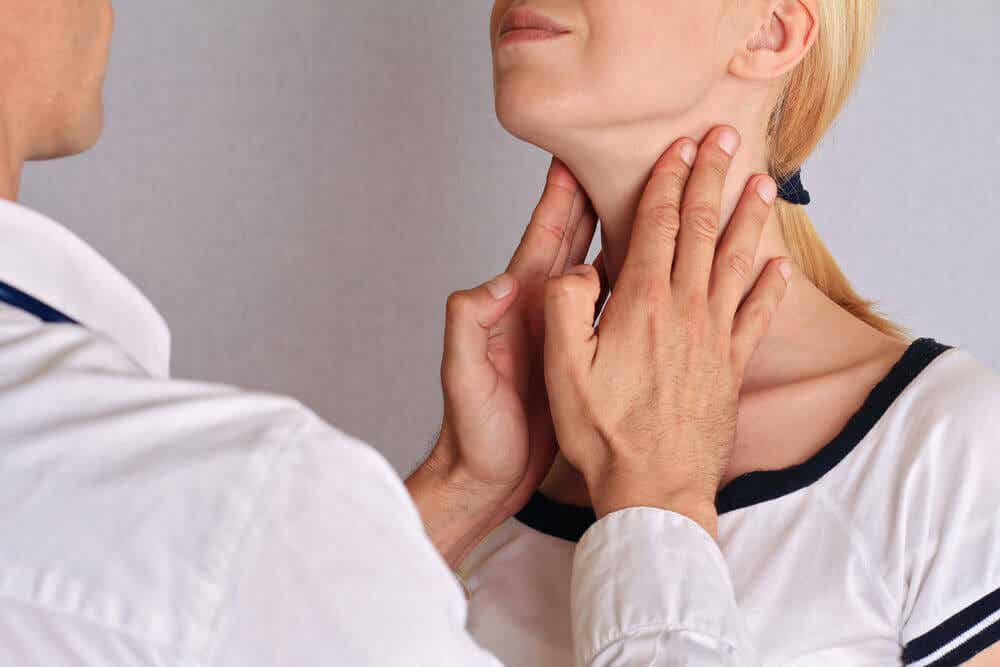 Médico examinando tiroides de una mujer.