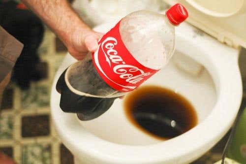 A person using cola soda to unclog a toilet.