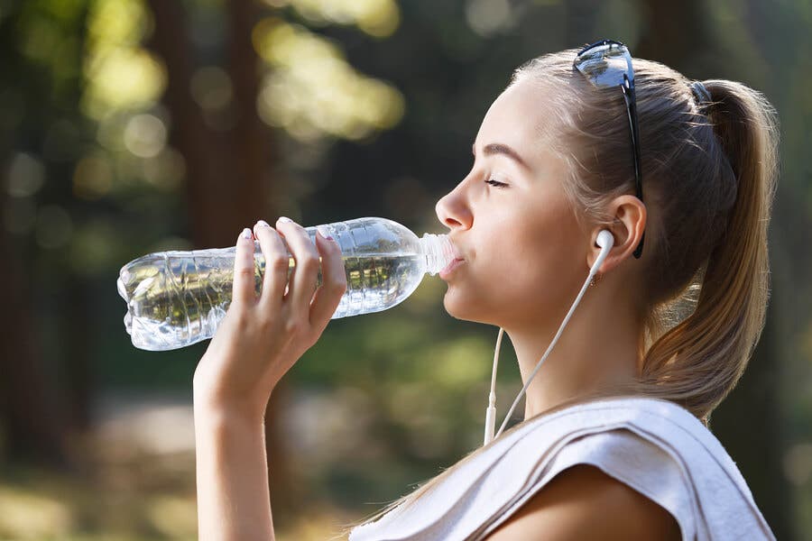 Chica bebiendo agua de una botella.