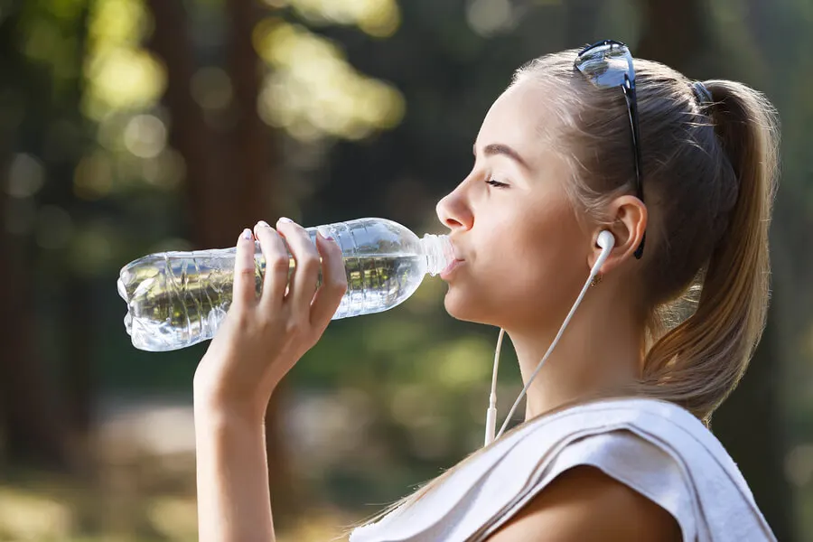 Chica bebiendo agua de una botella.