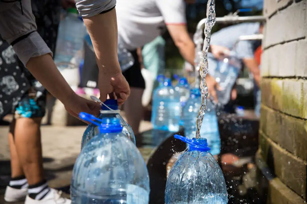 Personas rellenando botellas de plástico.