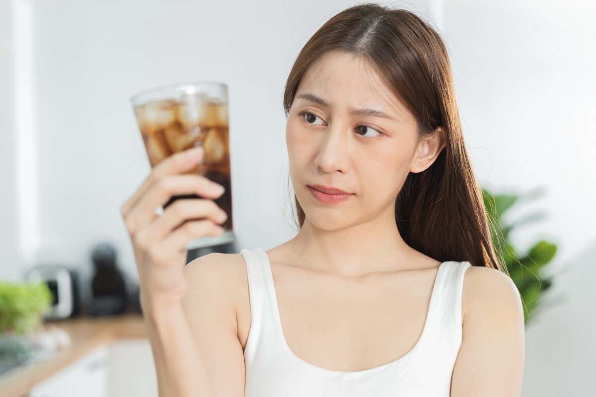 Kvinde ser skeptisk på et glas med sodavand