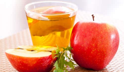 A glass of apple cider vinegar with two apples