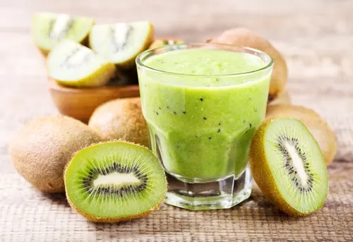 Licuado de kiwi rodeado de kiwis cortados