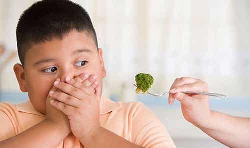 Niño obeso rechazando brócoli