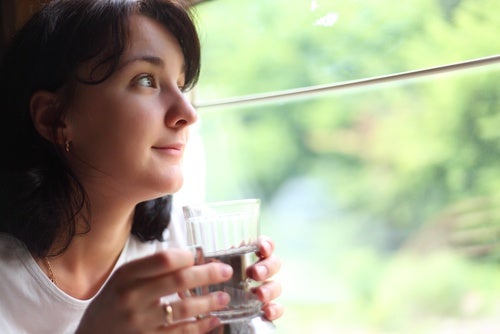 Mujer bebiendo agua en una ventana