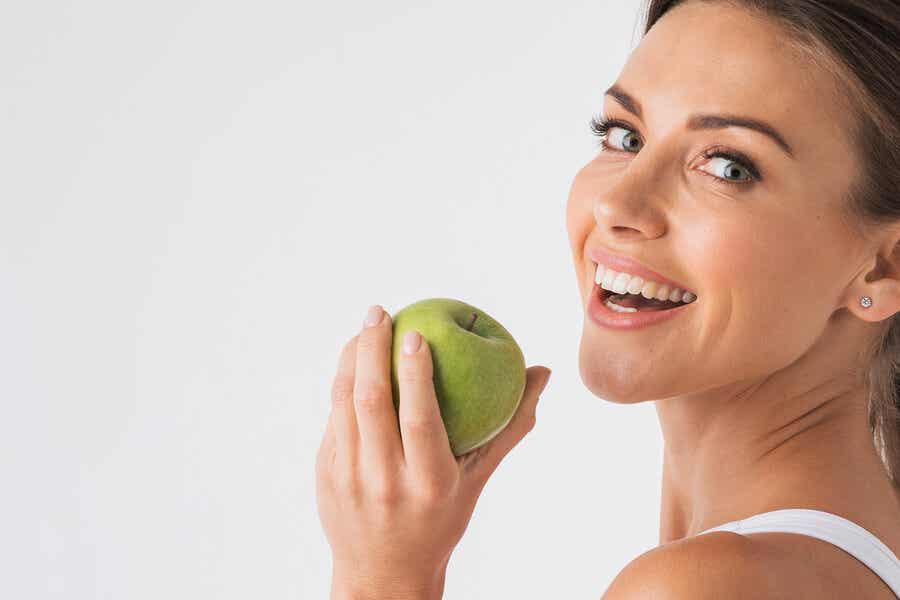 Femme souriante avec une pomme verte à la main.