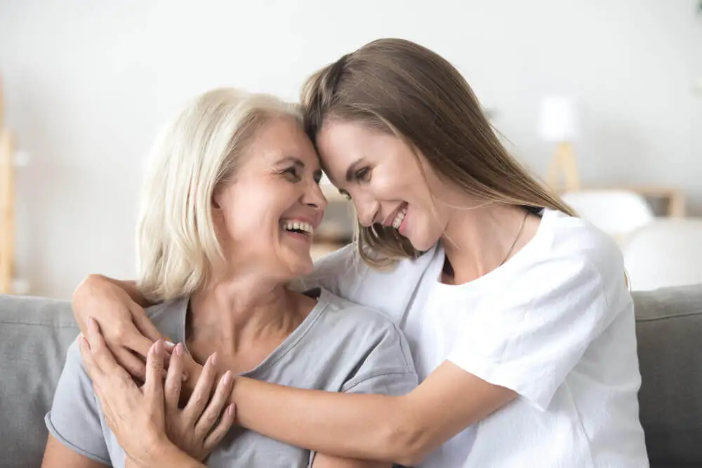 Hija y madre abrazadas sonriendo.