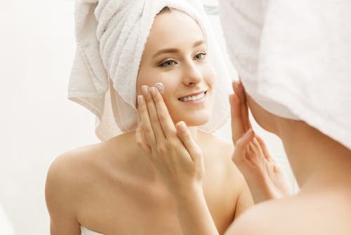 Mujer echándose crema en el rostro